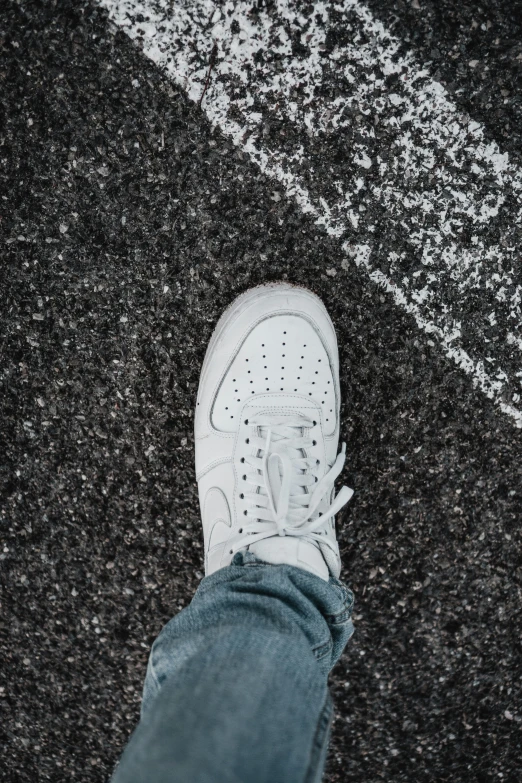someone standing on a paved area wearing all white sneakers
