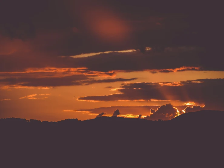 a sunset over mountains with a sky background