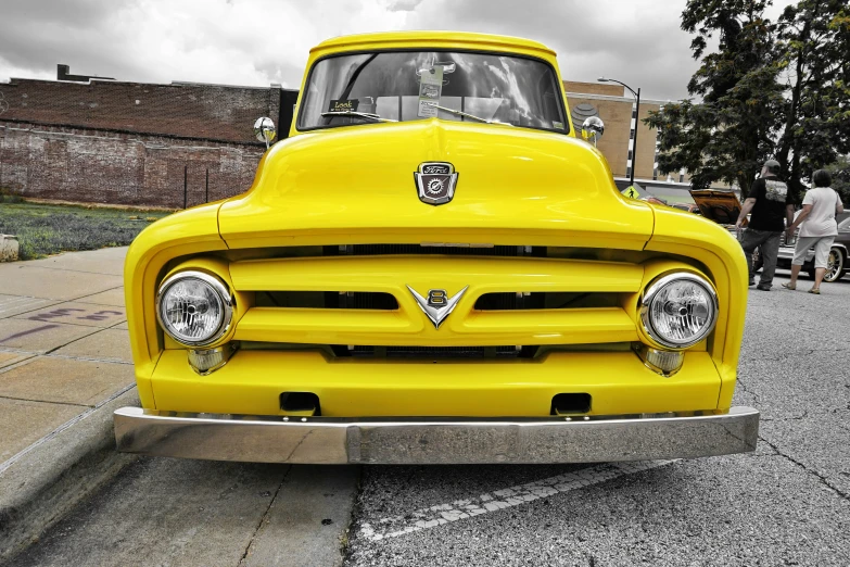 a yellow vintage truck parked next to a sidewalk