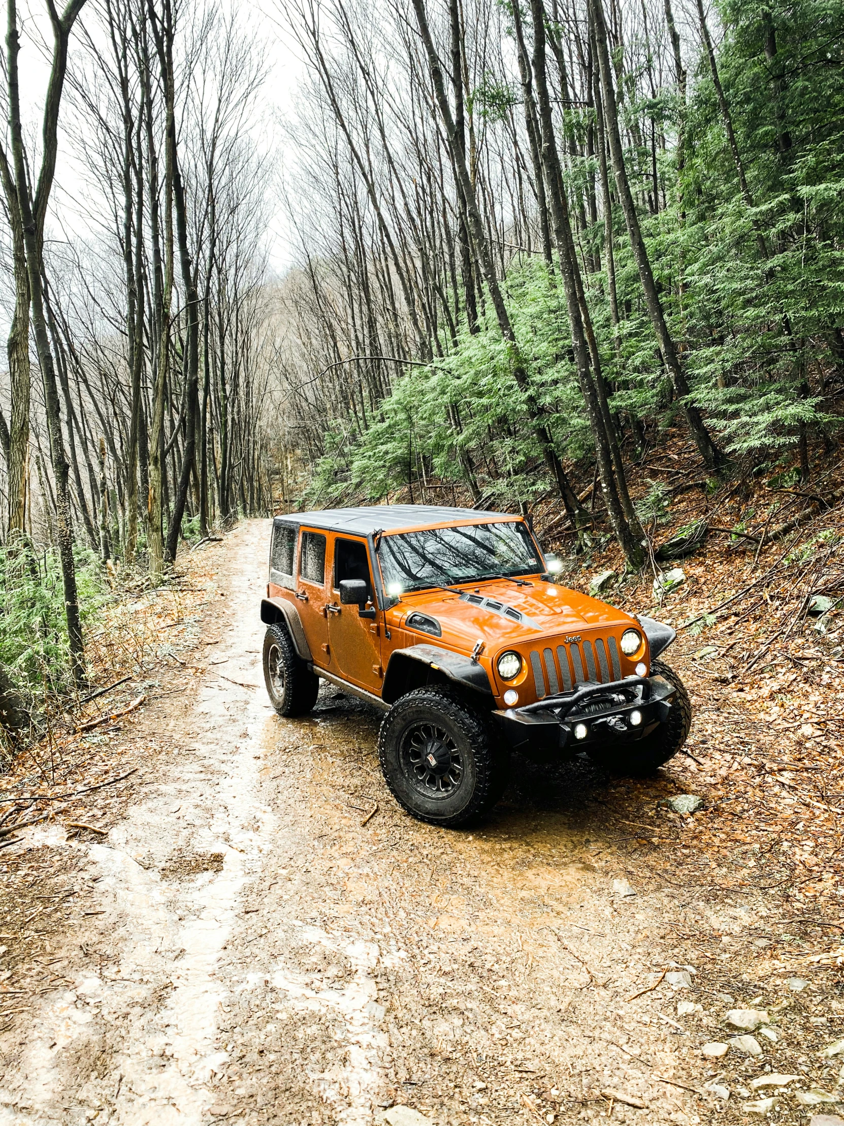 an orange truck traveling down a dirt road