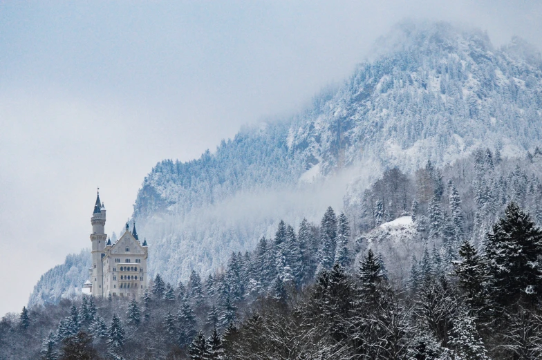 a castle stands atop a mountain covered in snow