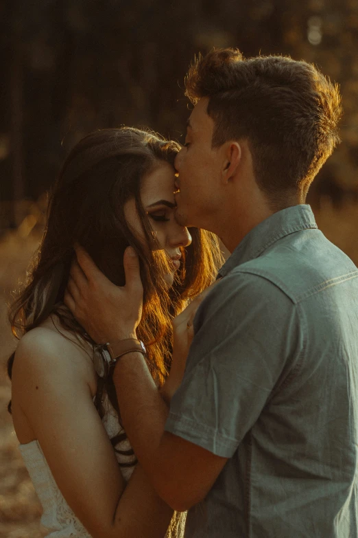 a couple kiss in an open field, at sunset