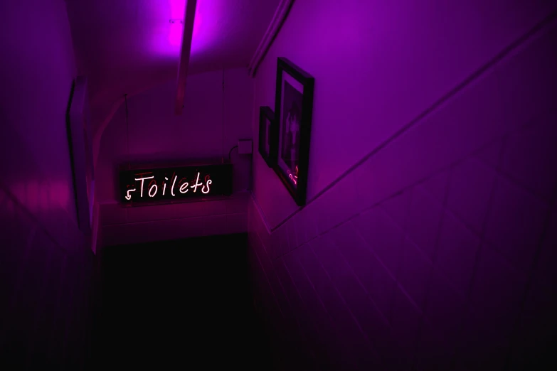 a purple colored lit hallway leads up to the exit