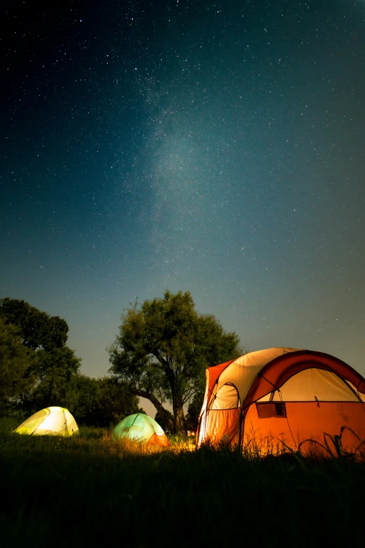 a tent with its roof opened next to a tree in the dark