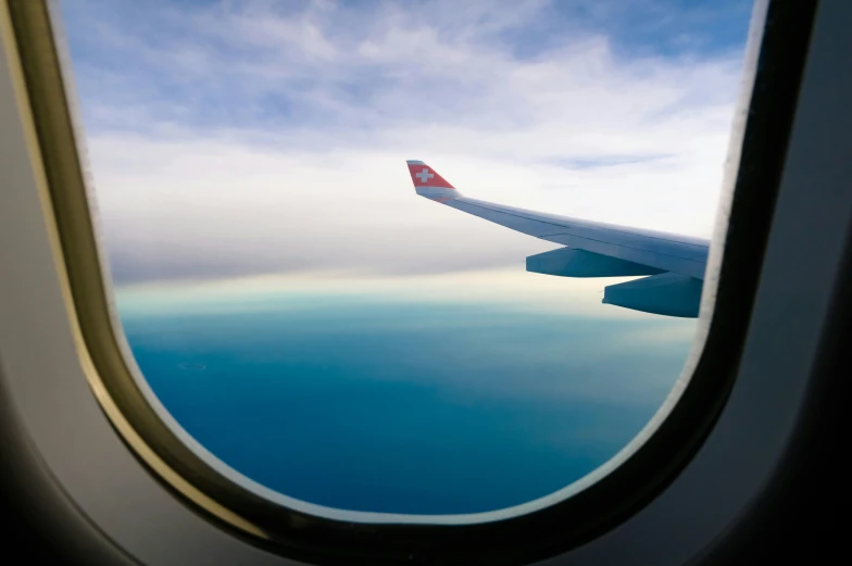 a window inside an airplane wing flying over water