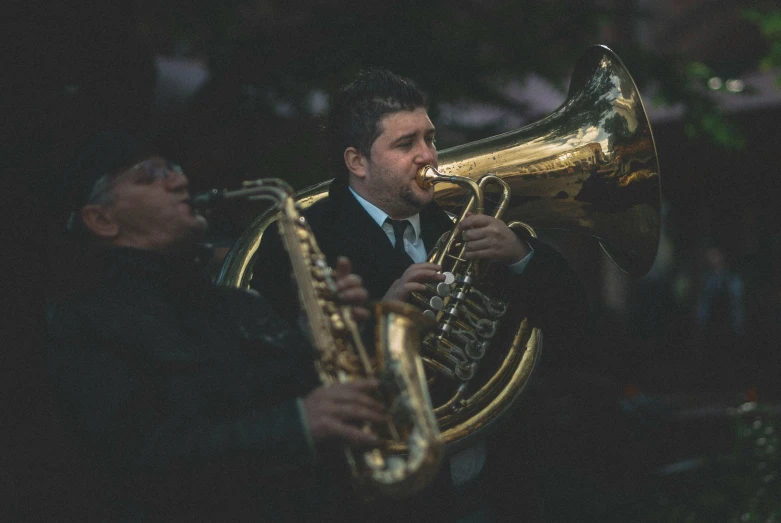 man in suit playing on ss trumpet outside at night