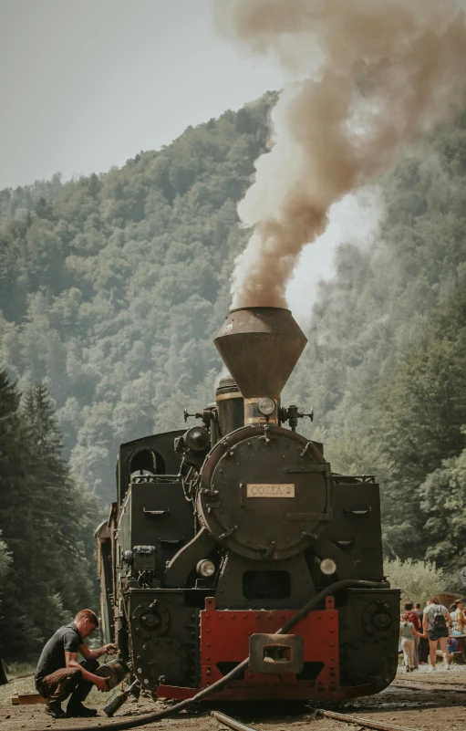 an old fashioned steam locomotive and man working on it