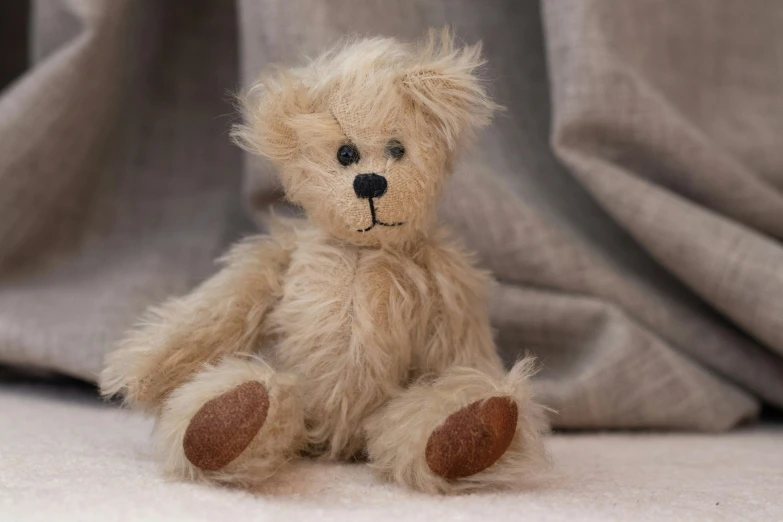 a brown teddy bear sitting on the ground