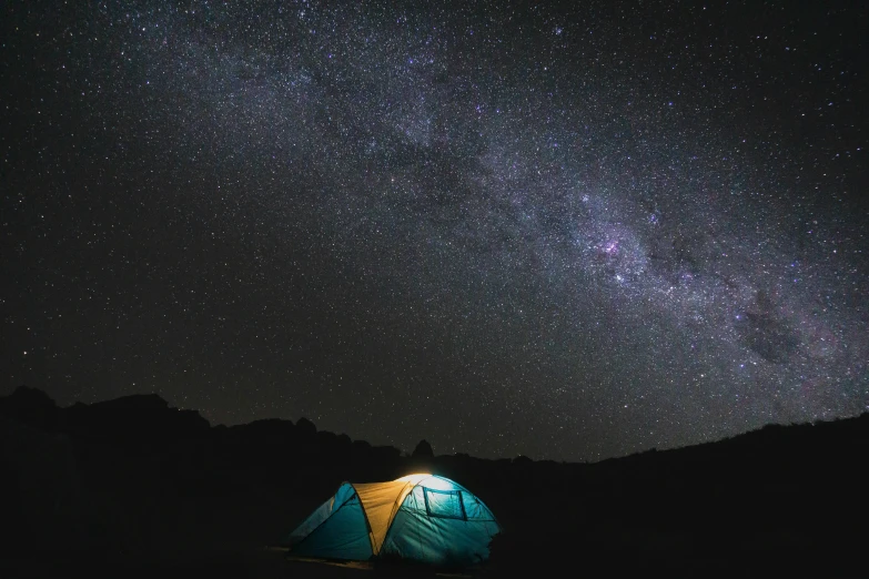 a blue and yellow tent is under a dark sky