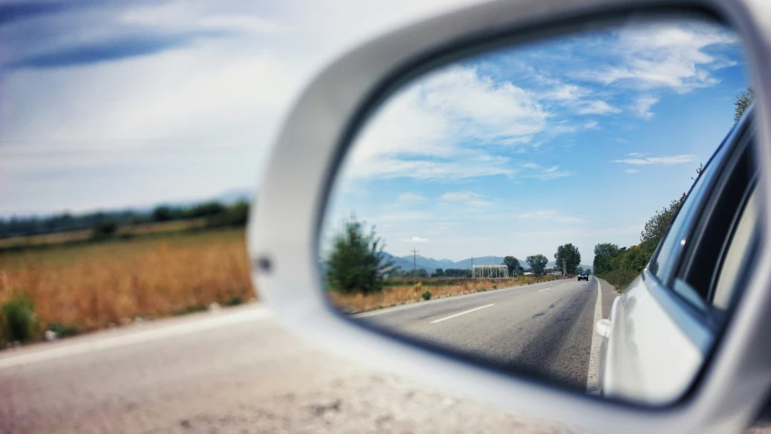 the view through the rear view mirror of a car's side window on the highway