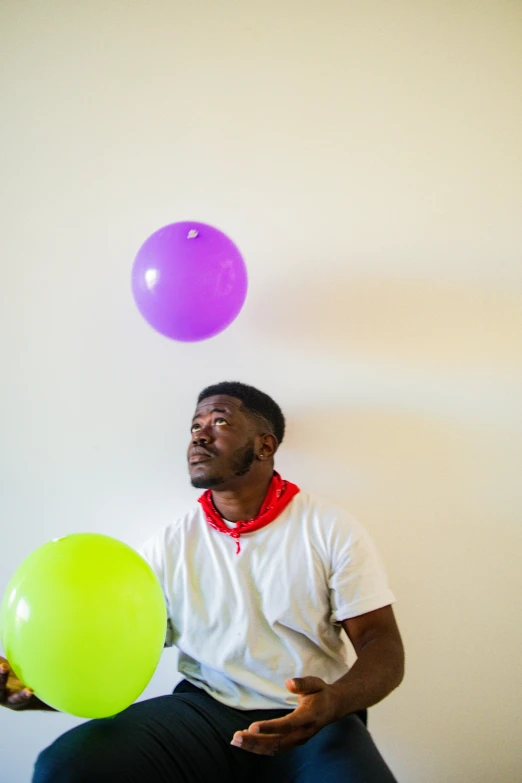 a man holding a ball with balloons behind him