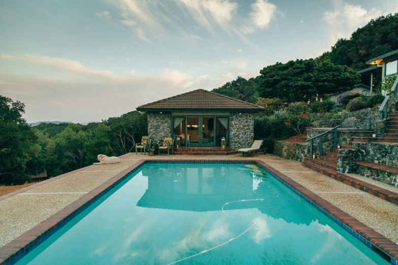 an outside pool area next to a wooded hillside