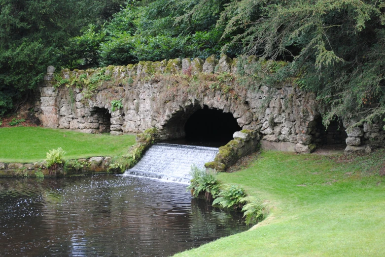 a small river running under a bridge next to a stone arch