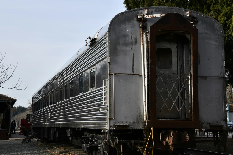 a gray train is on some tracks by a tree