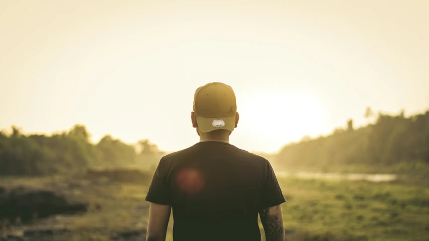 a man walking on a road wearing a baseball cap