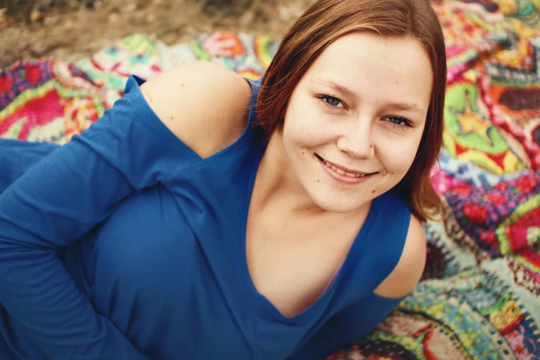 a woman in blue shirt laying on blanket