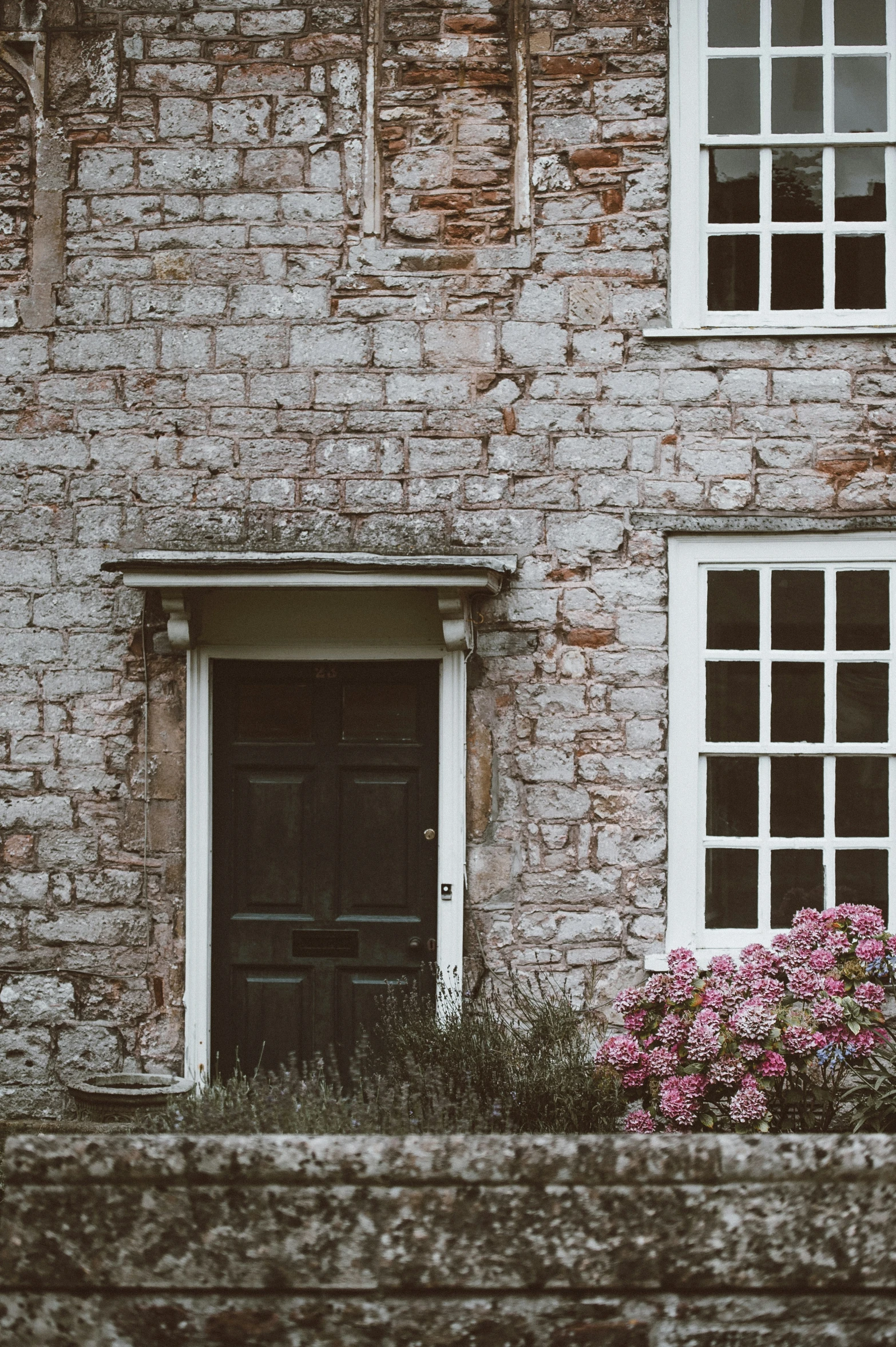 a stone building with window and a plant on the side