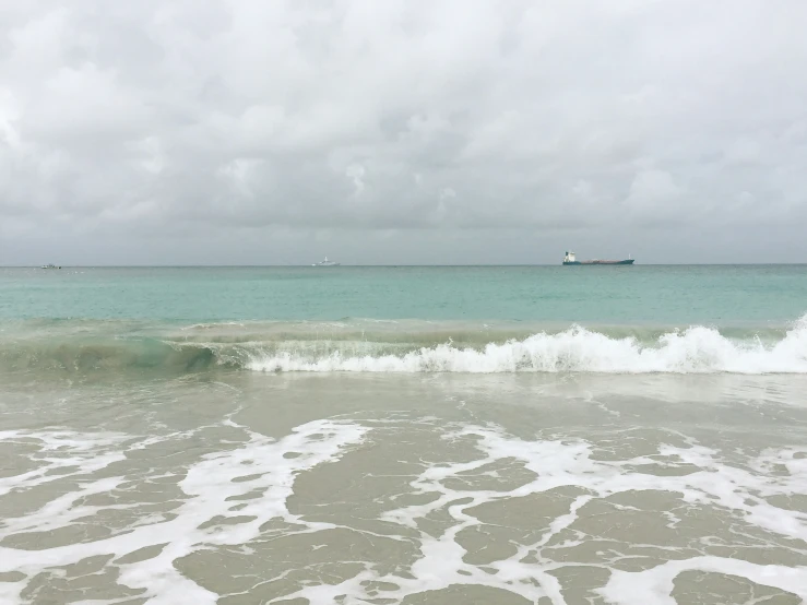 a ship out on the ocean next to a beach