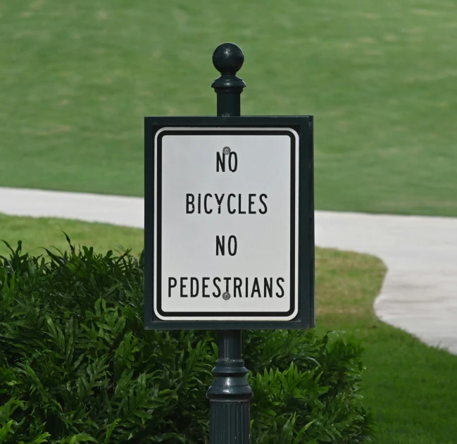 a no bicycles sign in front of a green park