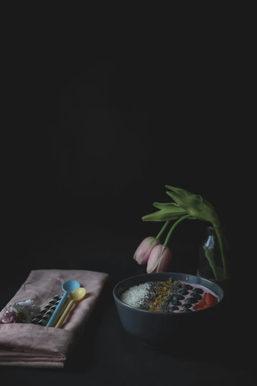 a flower is in front of a bowl with spoons