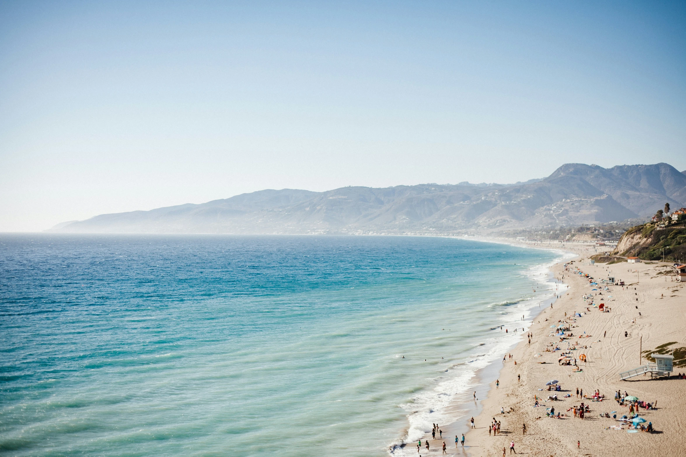 a beach that has people standing in the sand on it