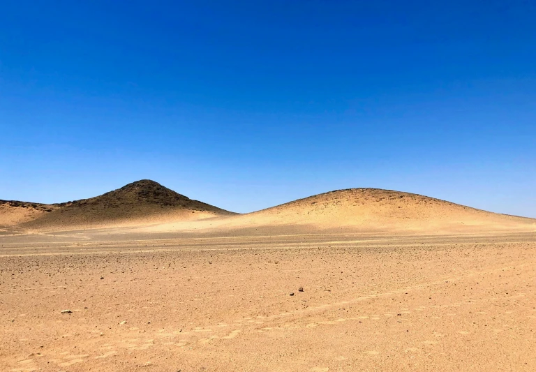 two large hills in the desert with blue sky