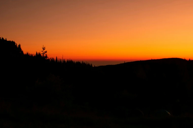 a sunset with trees and a mountain