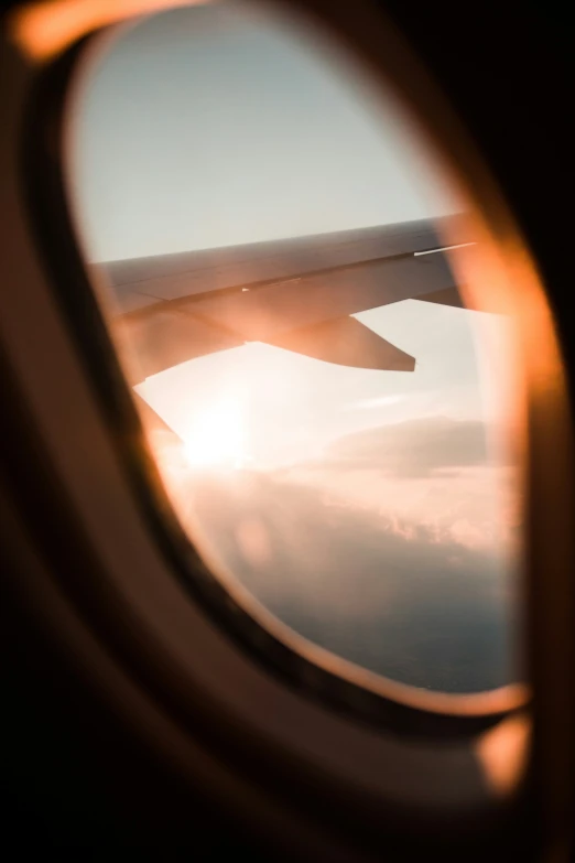 an airplane window looking at clouds and the sun