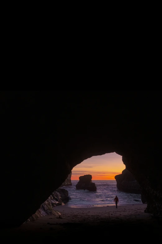 a man is standing in a large cave at the beach