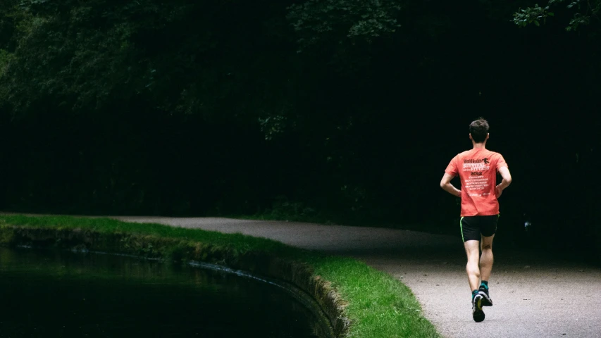 man jogging at night with a river behind him