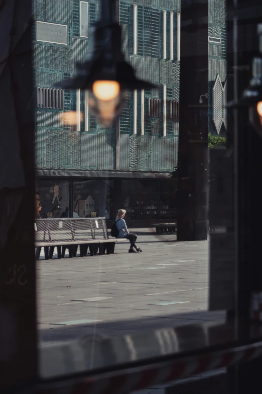 a man sits alone on a bench in a city