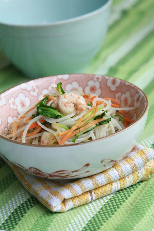 a bowl of food containing shrimp, carrots and noodles