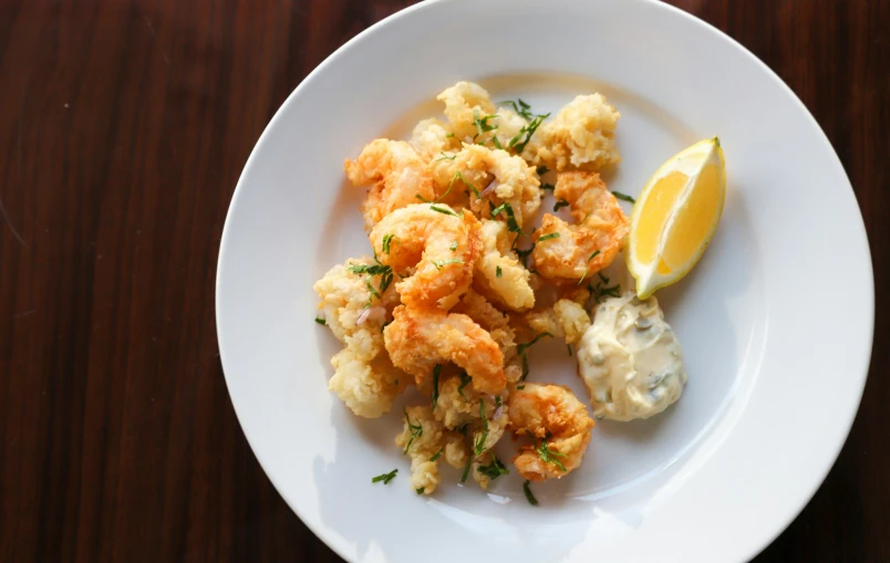 a plate full of fried food with some garnish and a lemon wedge