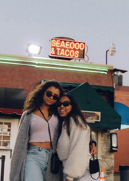 two women posing outside of a bar together