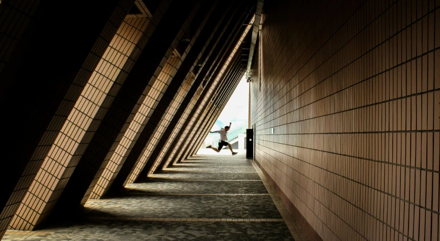 a boy in dark clothes is jumping through a corridor