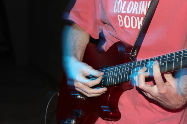someone is playing a guitar and wearing a red t - shirt