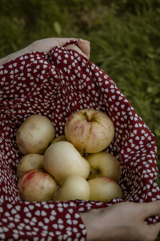 a basket full of apples sitting on a table outside