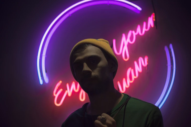 a young man posing in front of a neon circle