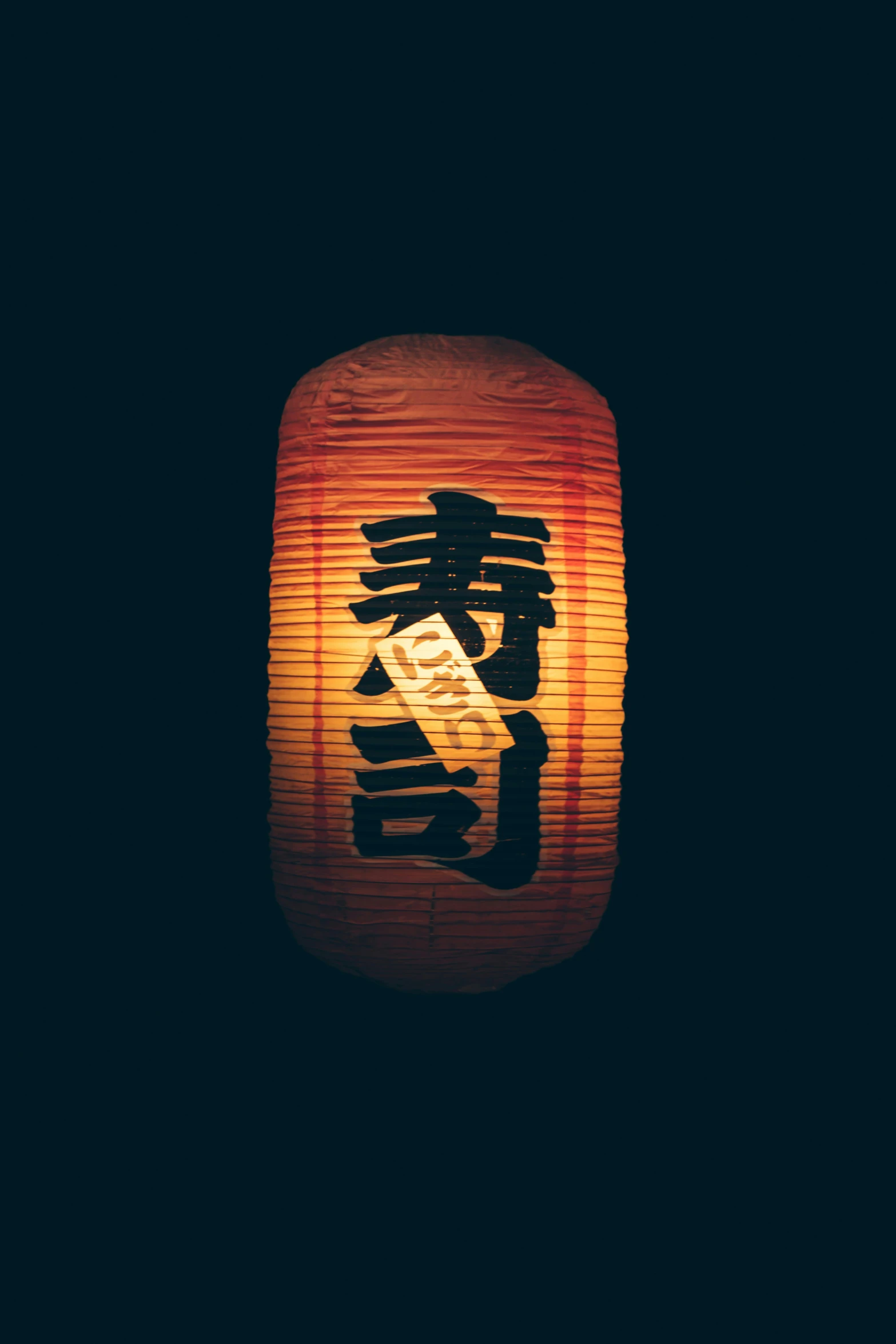 two red lanterns sitting in front of a black background