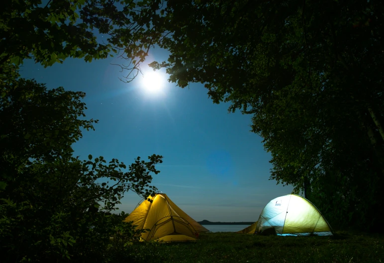 two tents on the ground near the water