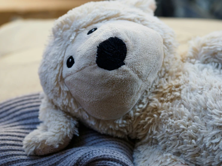 a brown teddy bear laying on top of a pillow