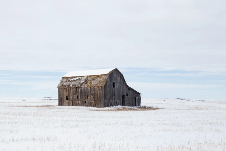 an old barn in a snowy field is shown