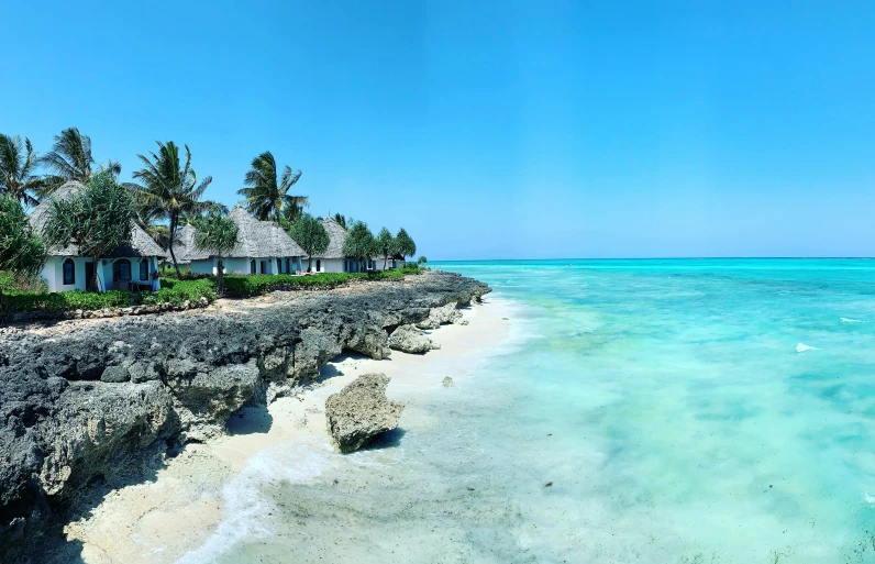 a deserted beach with white house in the distance