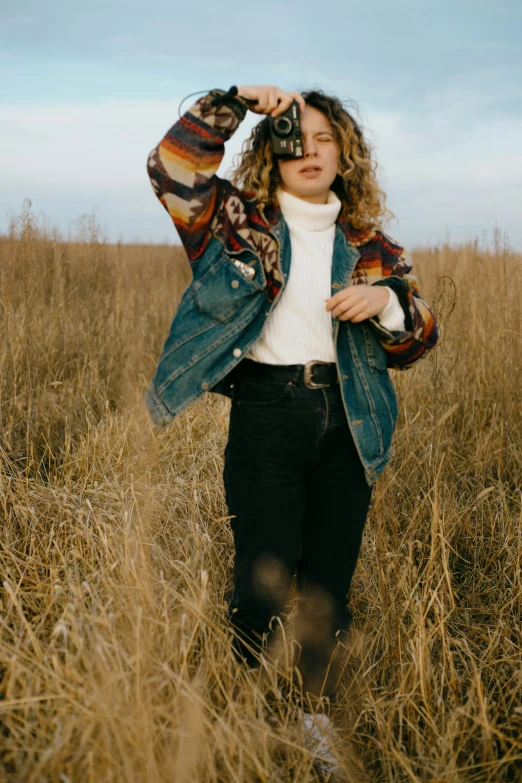 a woman standing in some tall grass on a sunny day