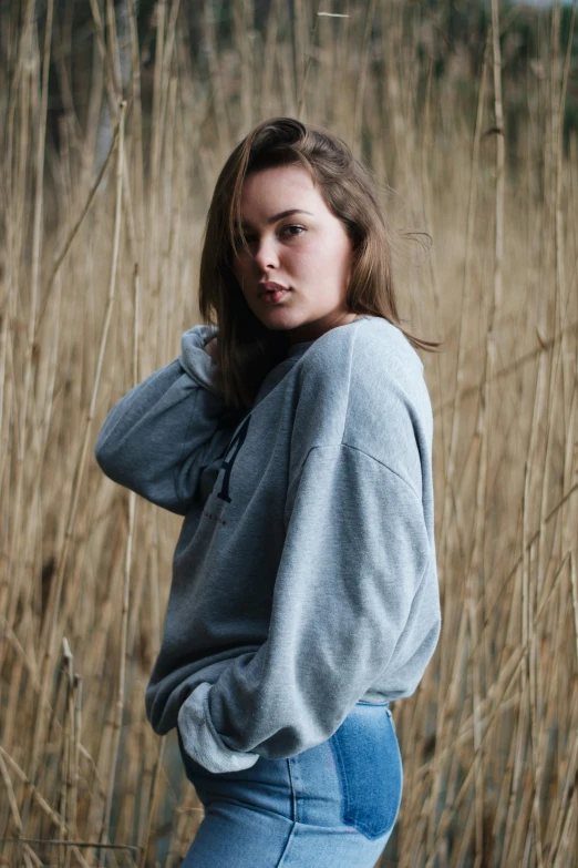 a woman standing in tall brown grass next to the grass