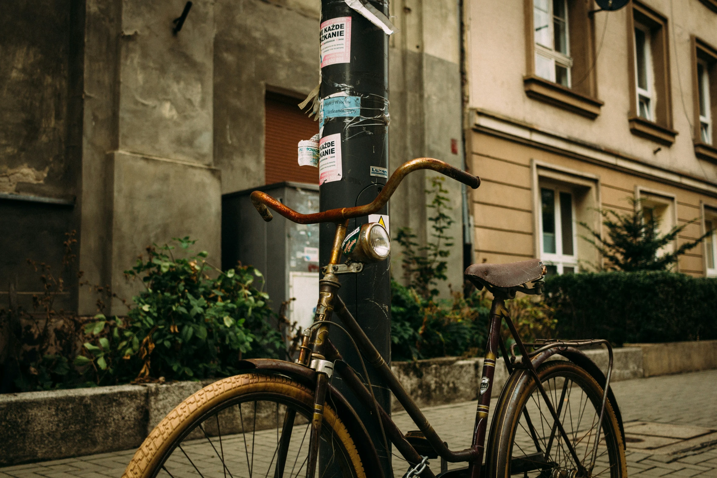 a bicycle parked in front of a pole with various stickers