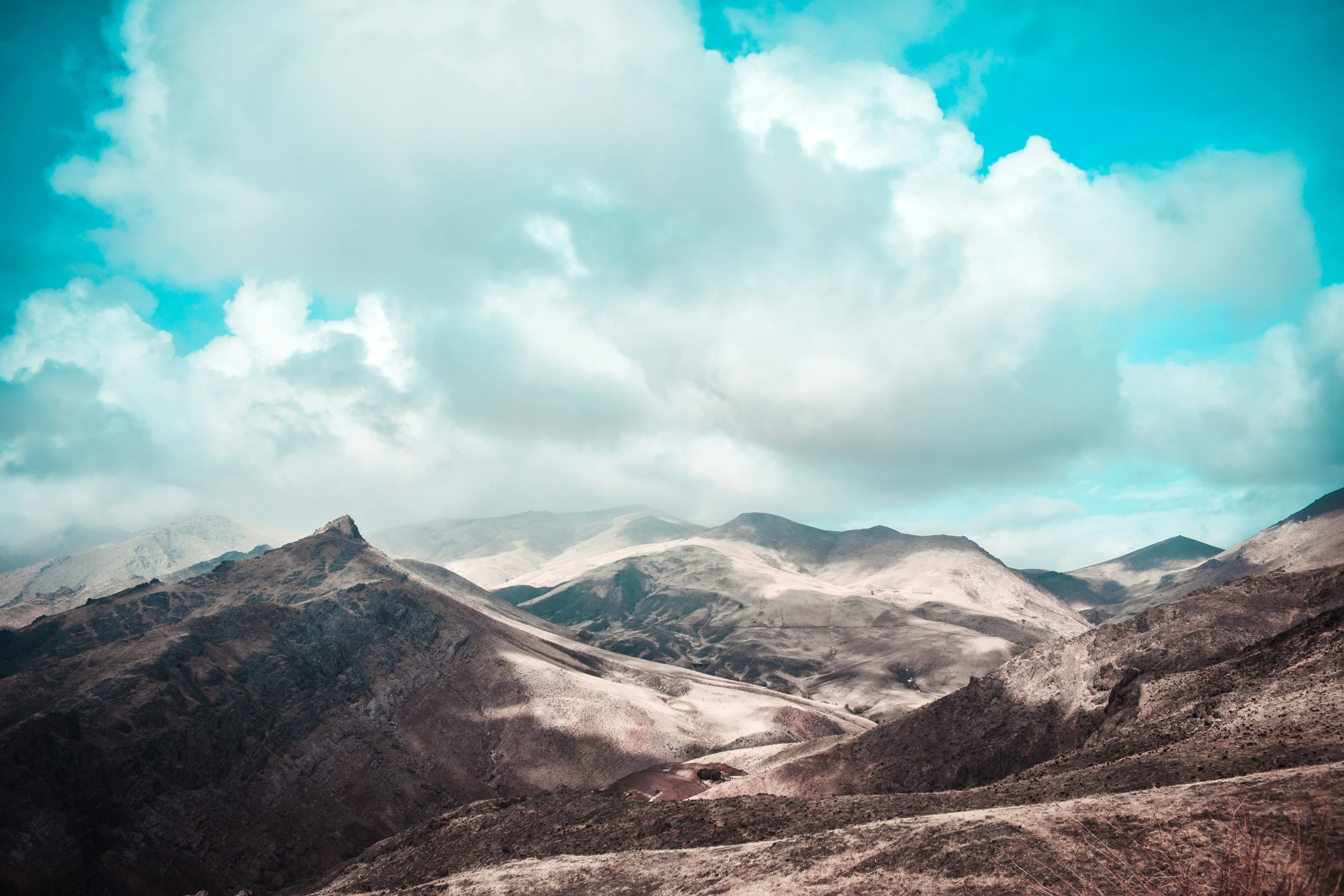 mountains are covered in white and brown color under cloudy skies