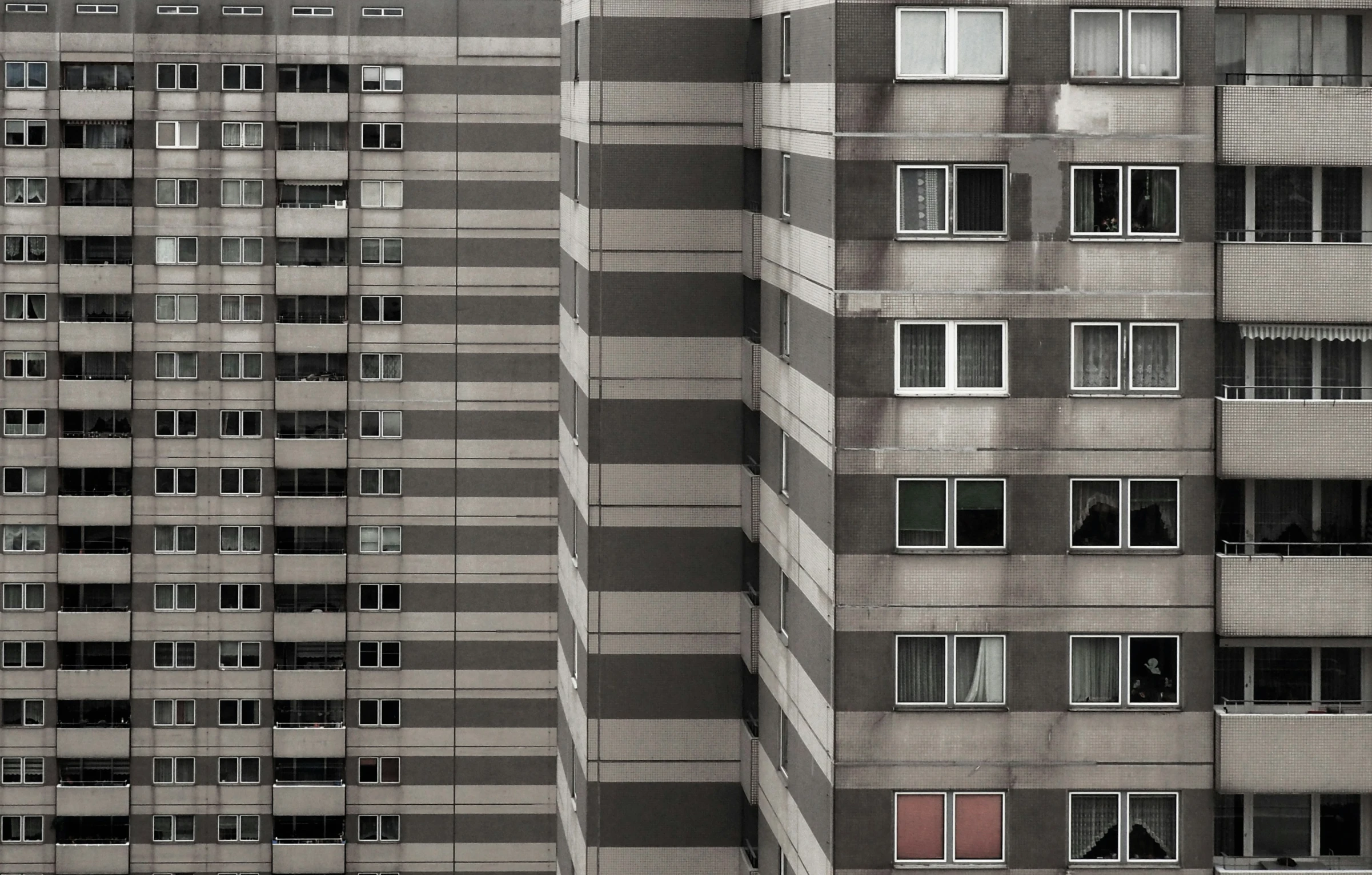 two tall buildings with windows and one is a red stop light