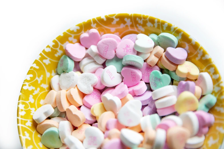 a yellow bowl filled with hearts on top of a table