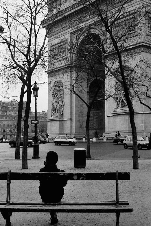 person sitting on bench in black and white city park